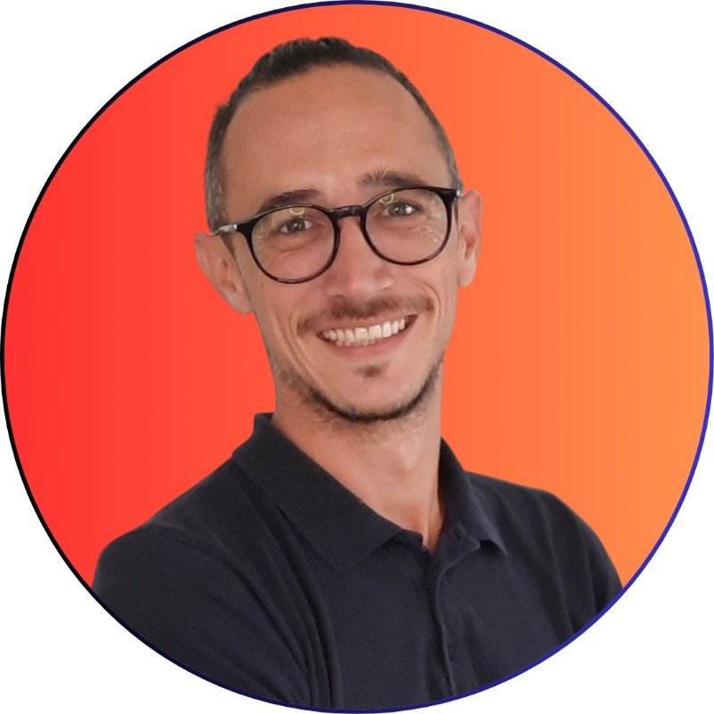 Homme souriant avec lunettes et fond orange.